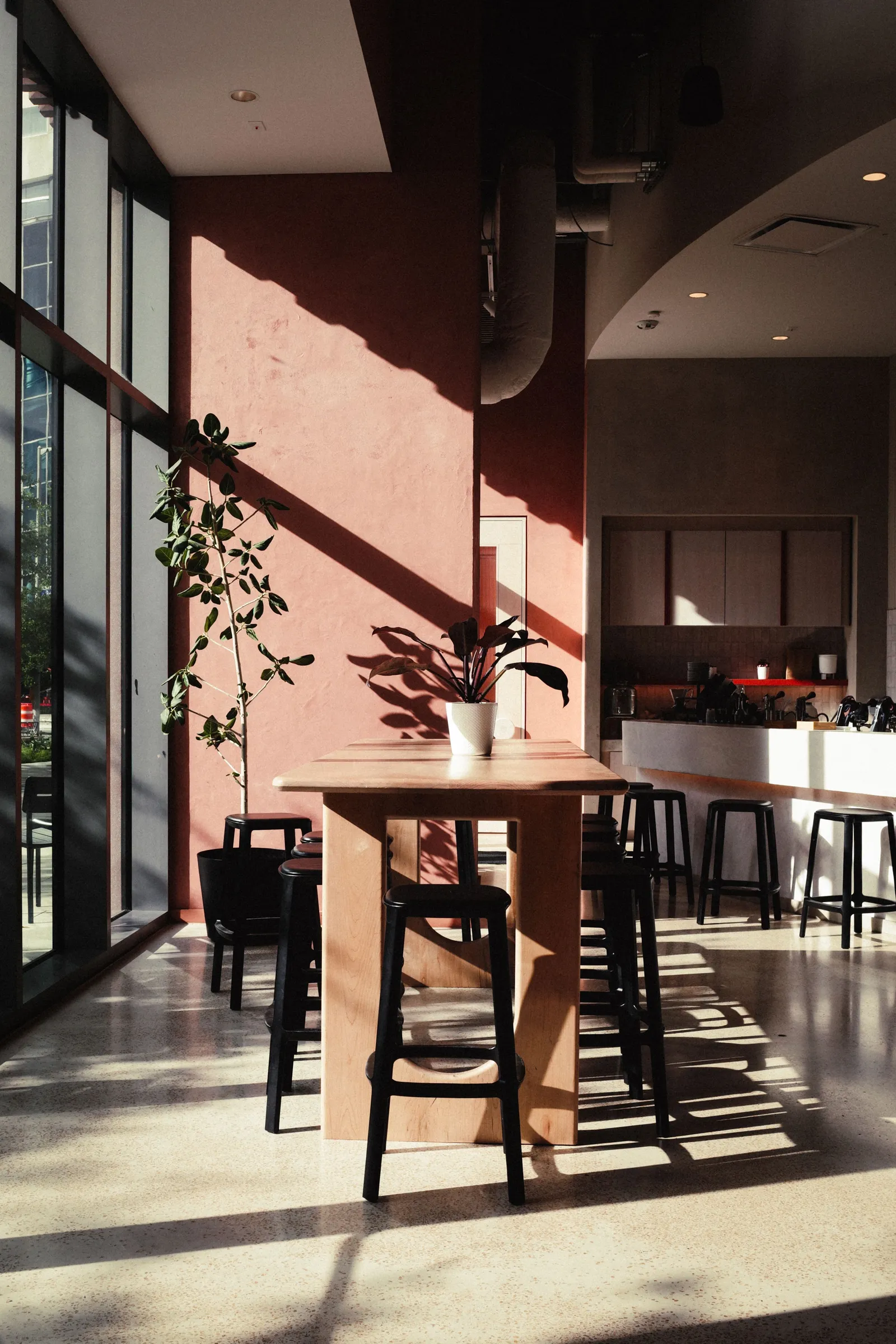 Wooden table against a pink-terracotta wall, long diagonal shadows across it